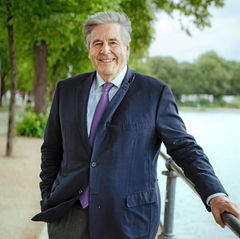 Josef Ackermann mit werwehtem Haar bei einem Besuch in Hamburg an der Alster