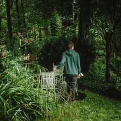 Schizophrenie: ein junger Mann steht in einem Garten