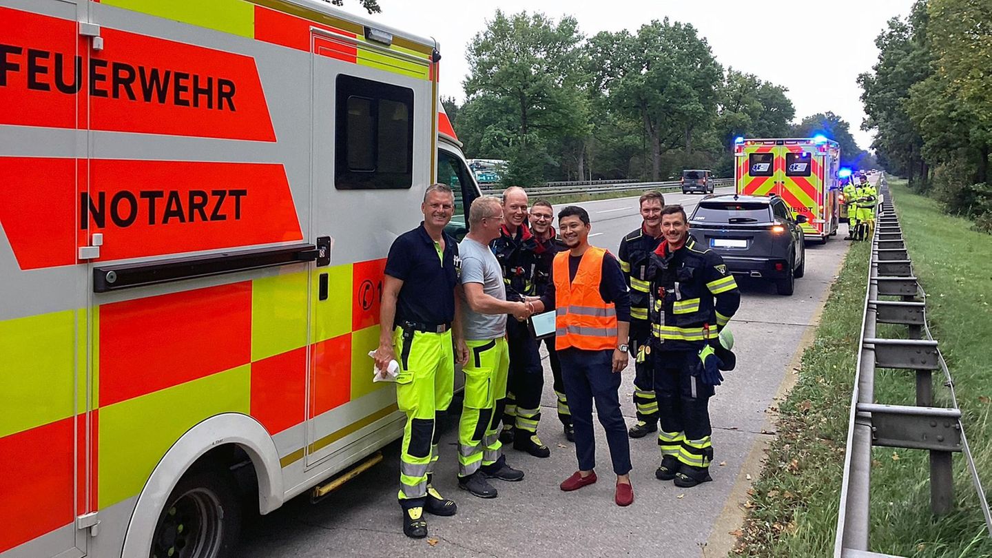 Die Feuerwehrbesatzung und der glückliche Vater nach der Geburt auf dem Standstreifen