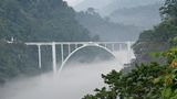 Brücke über einen Fluss, im Tal liegt Nebel