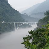 Brücke über einen Fluss, im Tal liegt Nebel
