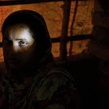 Eine Frau in einem dunklen Raum, nur ihr linkes Auge ist beleuchtet