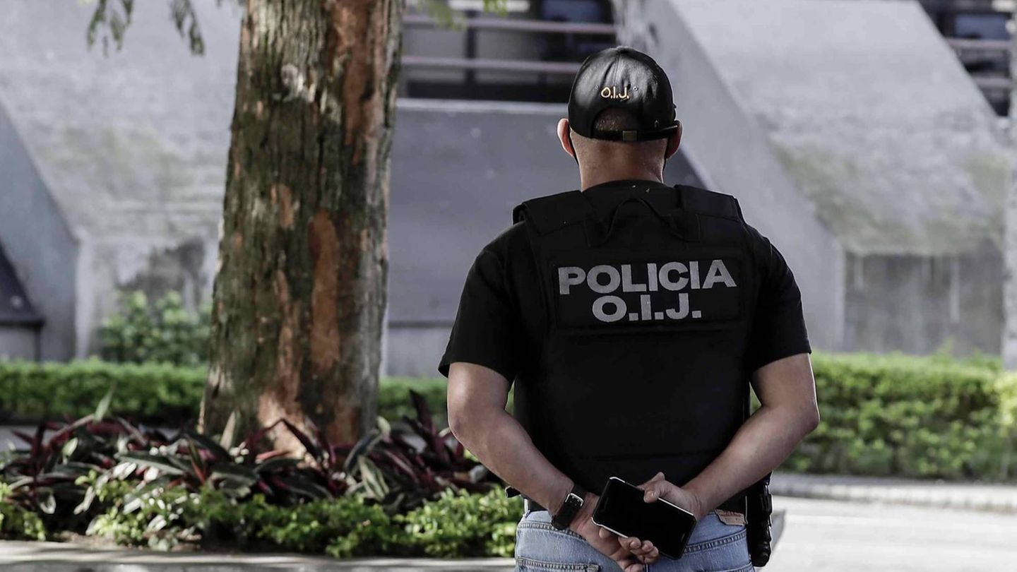 Ein Polizist in Costa Rica steht mit dem Rücken zur Kaemra. Auf seiner Weste steht "Policia O.I.J"