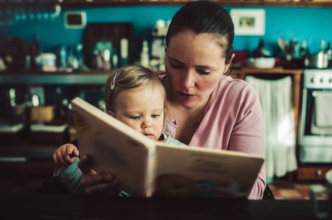 Alleinerziehend: eine Mutter liest ihrem Kleinkind ein Buch vor