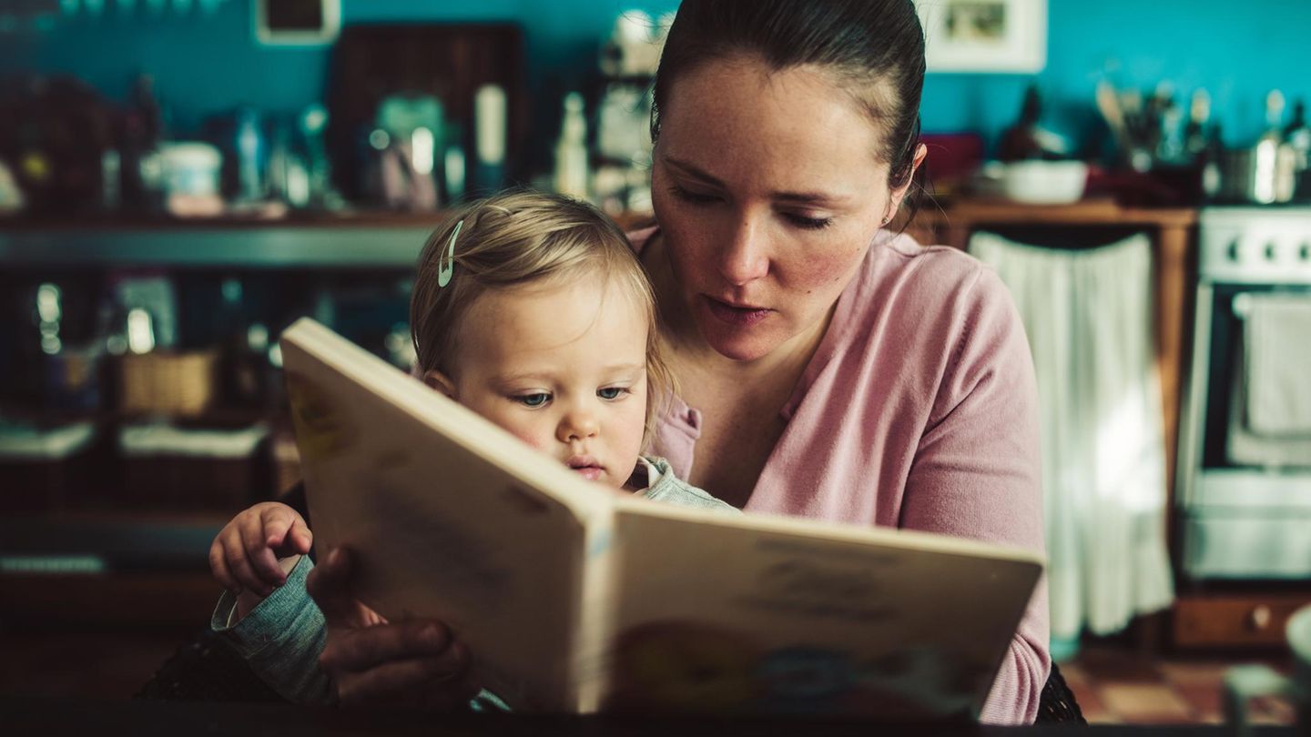 Alleinerziehend: eine Mutter liest ihrem Kleinkind ein Buch vor