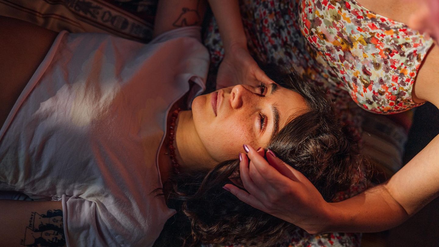 Frau liegt auf dem Schoß von ihrer Freundin