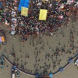 Menschen stehen in einem Fluss, drum herum sind Boote