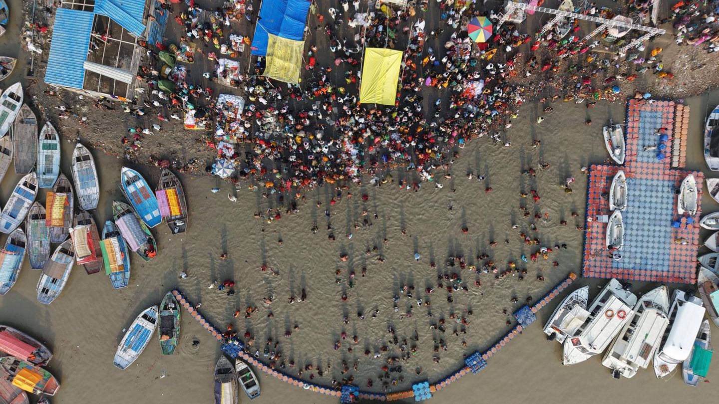 Menschen stehen in einem Fluss, drum herum sind Boote