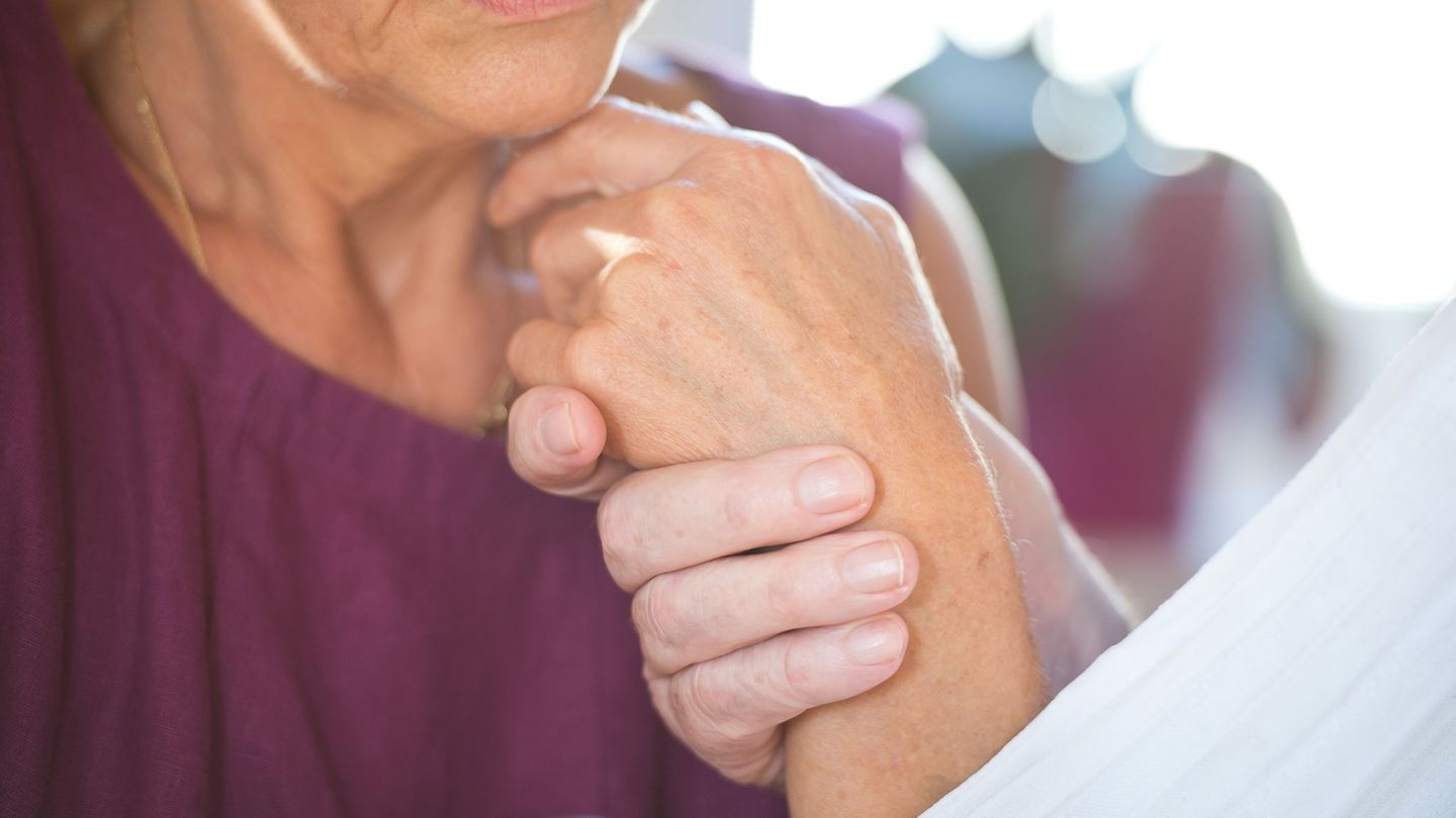 Eine Frau hält die Hand ihres an Demenz erkrankten Mannes. Foto: Daniel Naupold/dpa
