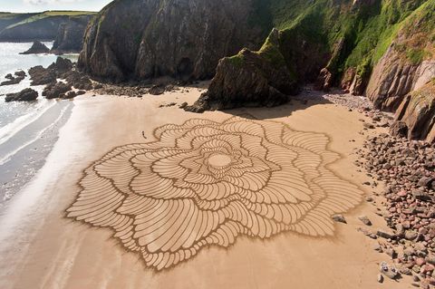 "Fluctuo" heißt dieses Werk des Künstlers Jon Foreman, er zeichnete es 2023 am Strand Lindsway Bay in Wales mit einem Laubrechen in den Sand – freihand, bis auf den Kreis in der Mitte