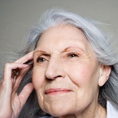Gedankenübertragung/Telepathie :Frau fasst sich an die Schläfen und schaut in die Ferne