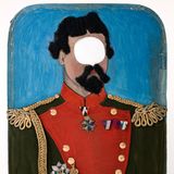 Ein bemaltes Schild, auf dem König Ludwig II abgebildet ist, mit einem Loch an Stelle seiner Augen