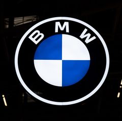Das erleuchtete Logo von BMW hängt in einer Halle
