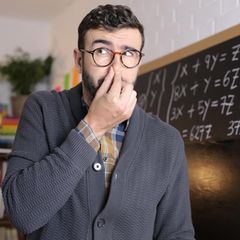 Ein Lehrer hält sich in der Schule die NAse zu