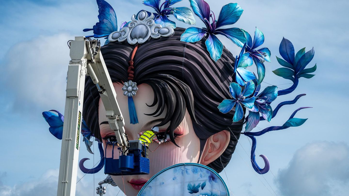 Hongkong, China. Bauarbeiter arbeiten an einer großen weiblichen Hanfu-Figur vor der Skyline der Stadt. "Hanfu" steht für einen historischen, chinesischen Kleidungsstil, der in die Kaiserzeit zurückreicht. Aktuell ist mit dem Begriff oft der Wunsch nach einer Wiederbelebung traditioneller, chinesischer Mode und Kultur verbunden