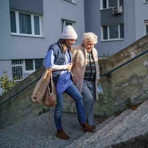 Eine Frau bringt mit einer älteren Dame die Einkäufe nach Hause