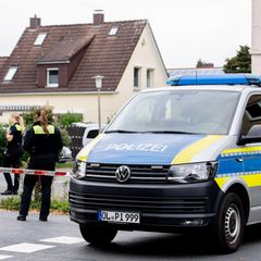 Polizisten stehen in einem mit Flatterband abgesperrten Bereich nahe des Tatorts in Oldenburg