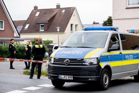 Polizisten stehen in einem mit Flatterband abgesperrten Bereich nahe des Tatorts in Oldenburg