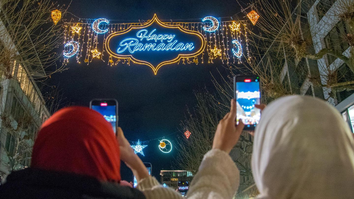 Passanten fotografieren mit ihren Handys die "Happy Ramadan" Beleuchtung