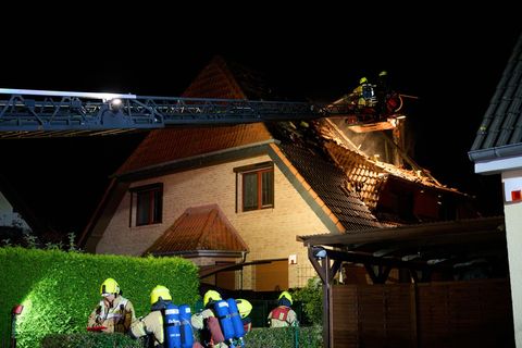 Einsatzkräfte der Feuerwehr stehen auf einer Feuerwehrleiter und löschen einen Brand in Marzahn. (Archivbild) Foto: Annette Ried