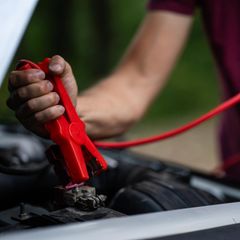 Person nutzt Starthilfe fürs Auto