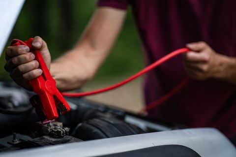 Person nutzt Starthilfe fürs Auto