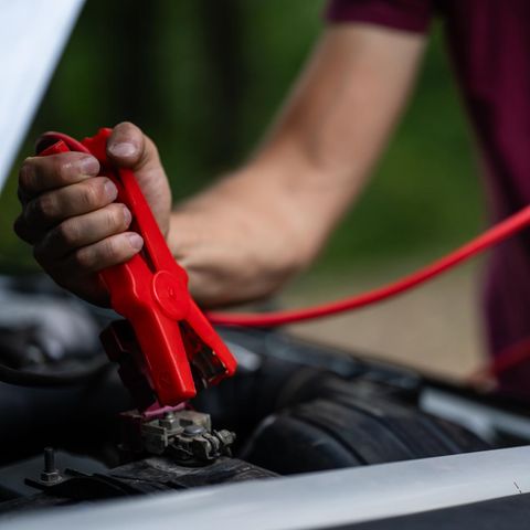 Person nutzt Starthilfe fürs Auto