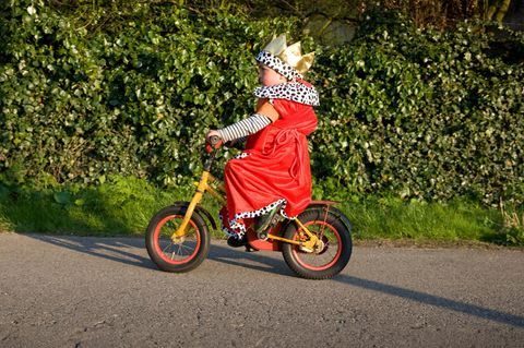 Kind im Königskostüm fährt Fahrrad