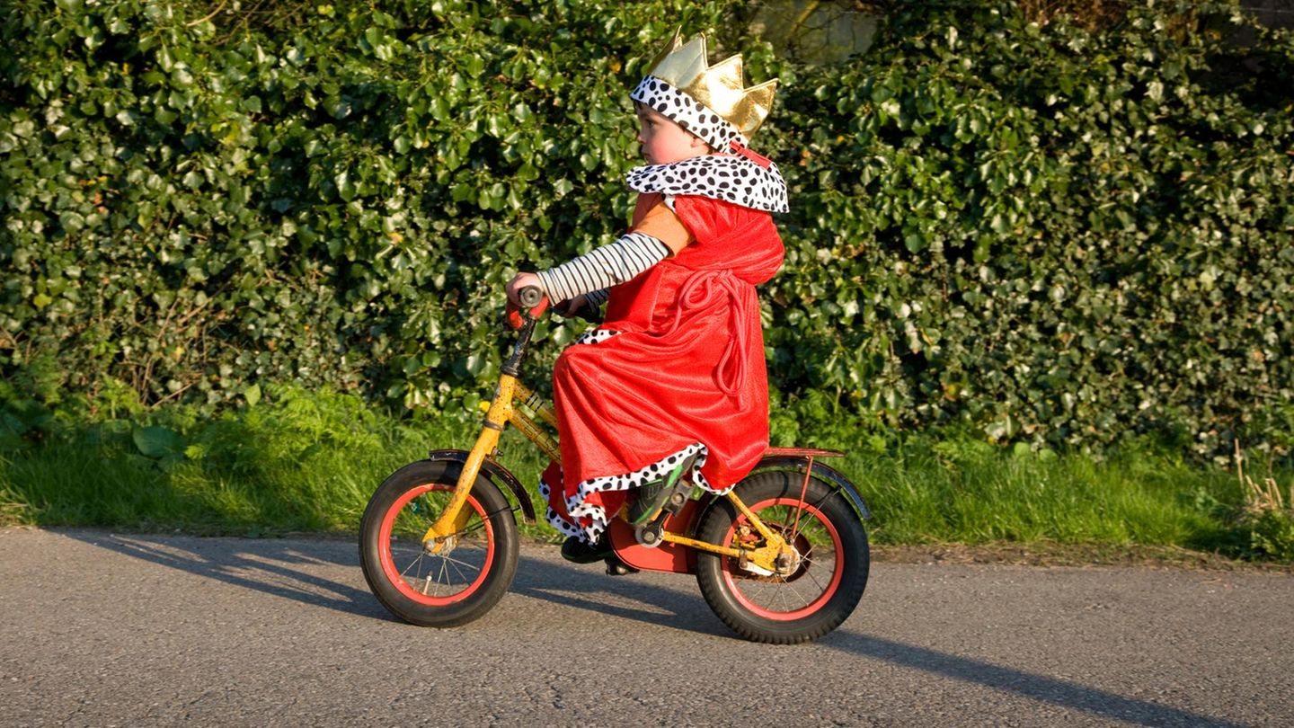 Kind im Königskostüm fährt Fahrrad