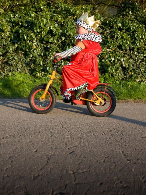 Kind im Königskostüm fährt Fahrrad