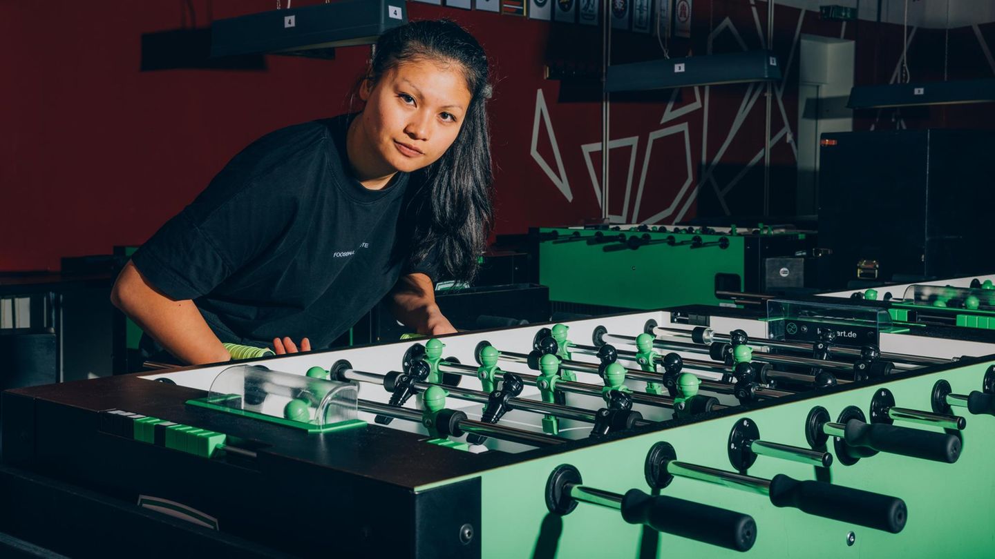 Weltmeisterin Linh Tran an einem Tischfußball leicht vorgebeugt in die Kamera blickend