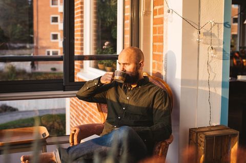 Mann trinkt einen Kaffe im Wintergarten