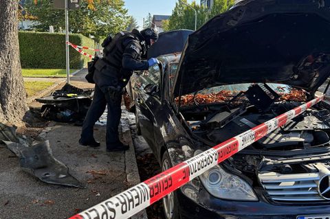 Ein Polizist untersucht eines der im Münchener Norden ausgebrannten Autos