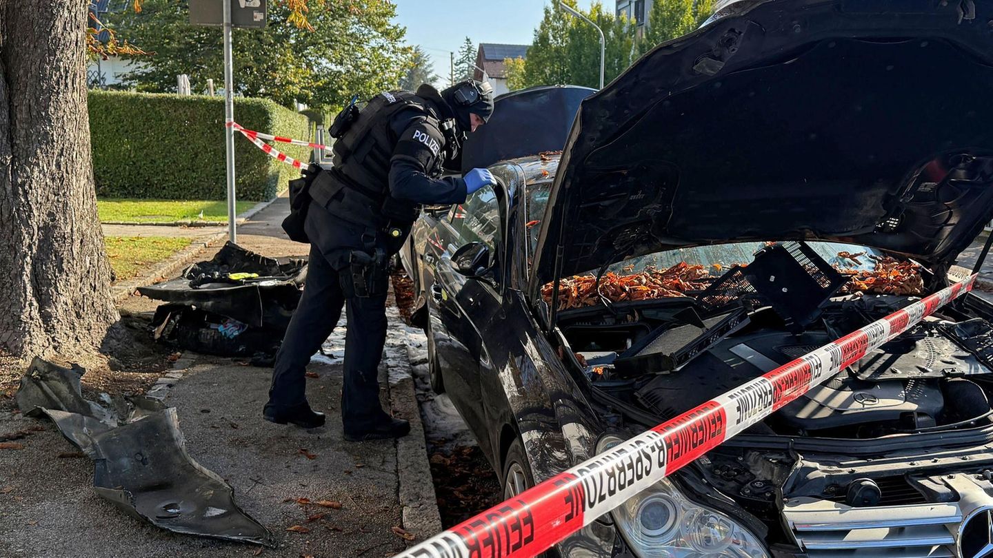 Ein Polizist untersucht eines der im Münchener Norden ausgebrannten Autos