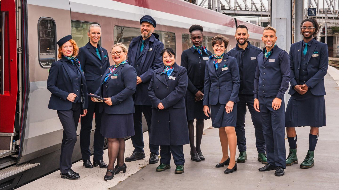 Zehn Menschen in genderneutralen Uniformen stehen neben einem Eurostar an der Gare du Nord in Paris
