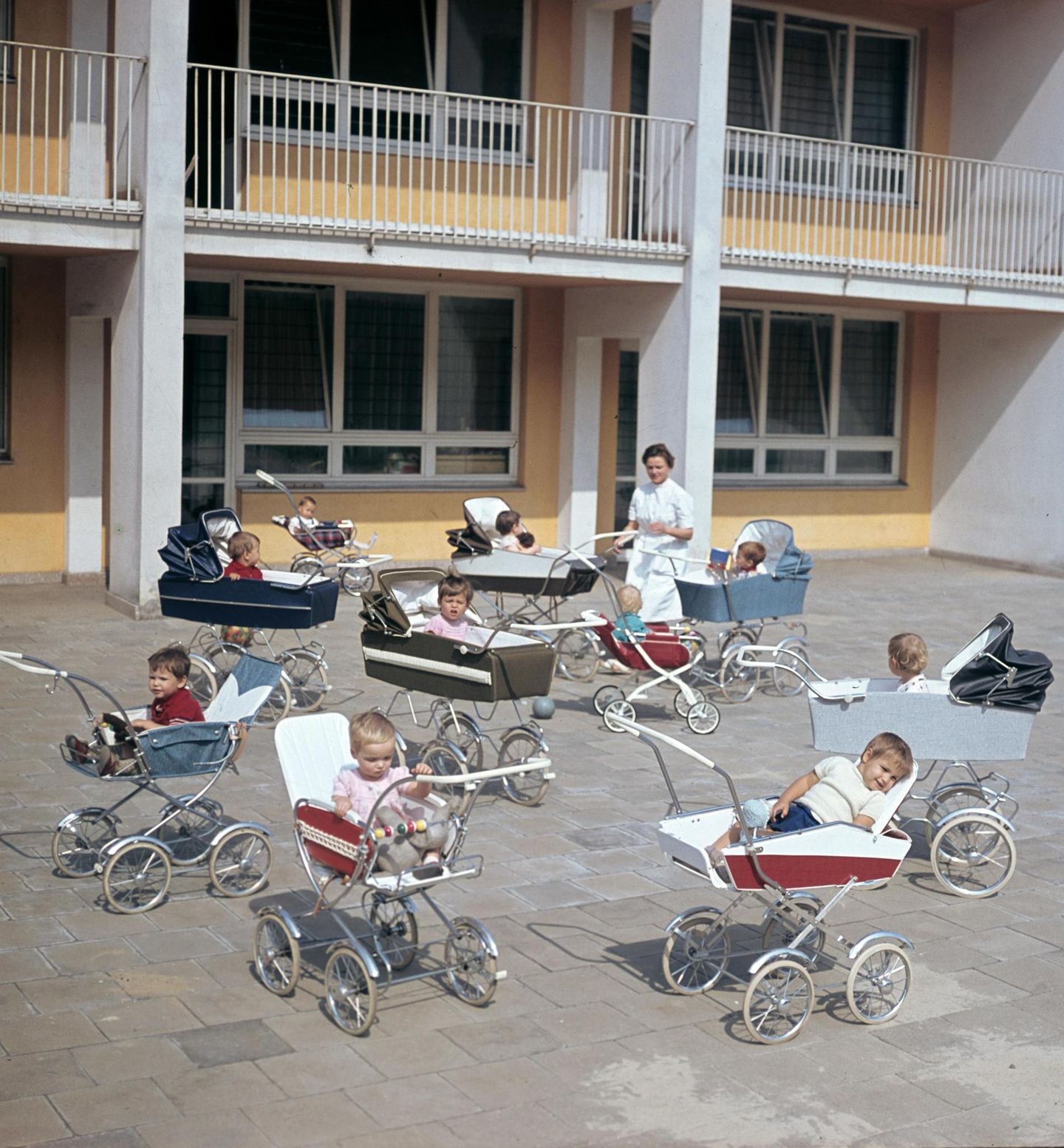 Staatliche Kindererziehung Gruppe Kleinkinder in Kinderwägen und Betreuerin