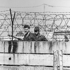 Zwei Grenzsoldaten hinter einer Mauer