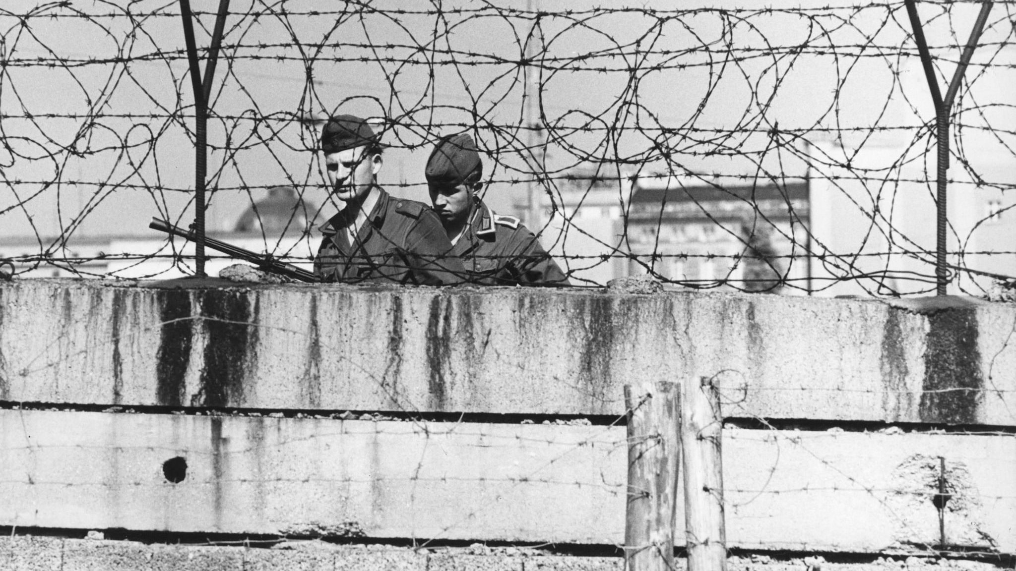 Zwei Grenzsoldaten hinter einer Mauer Zwei Grenzsoldaten hinter einer Mauer