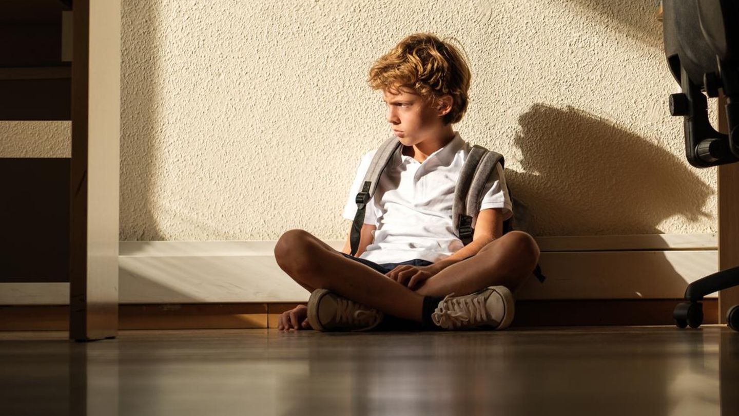 Kind sitzt in einem Klassenzimmer auf dem Boden