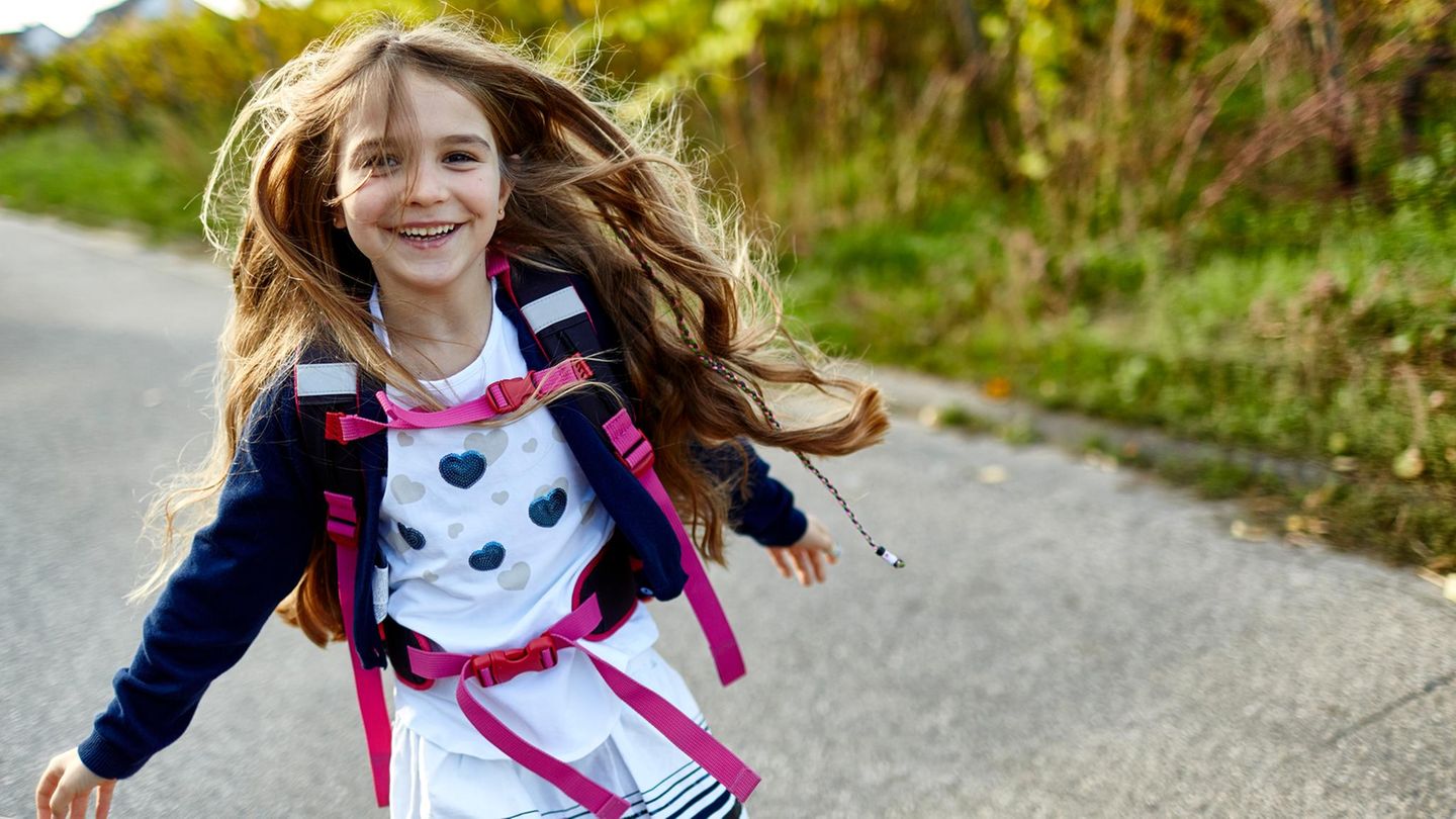 Kinder: Ein Mädchen mit Rucksack rennt