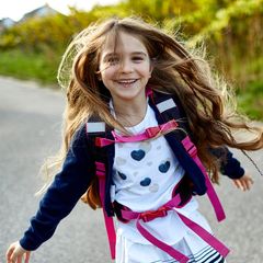 Kinder: Ein Mädchen mit Rucksack rennt