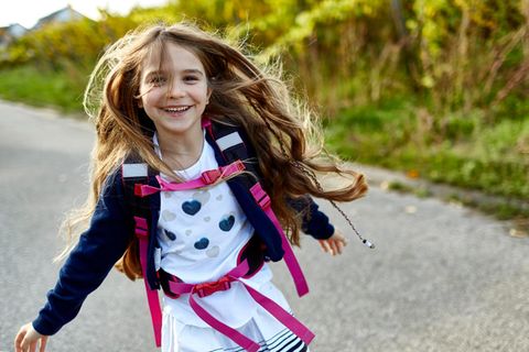 Kinder: Ein Mädchen mit Rucksack rennt