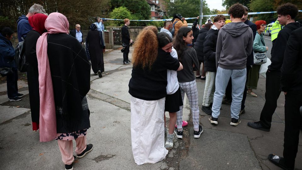 Menschen stehen in der Nähe der Synagoge, an der sich die Attacke ereignete. Einige umarmen sich, sind sichtlich schockiert