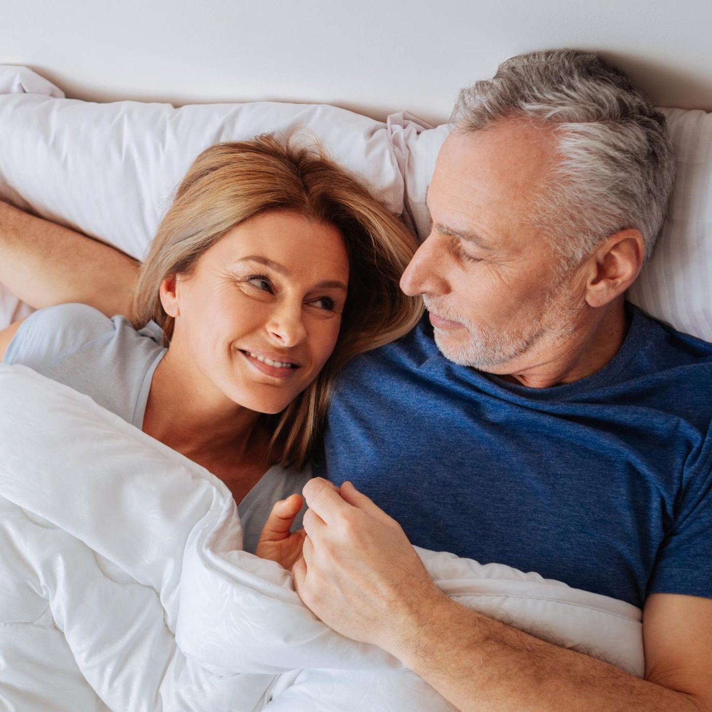 Ein älteres Paar liegt im Bett (Symbolbild Vasektomie)