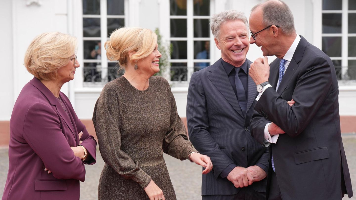 Das frische Paar feixt mit Kanzler Friedrich Merz