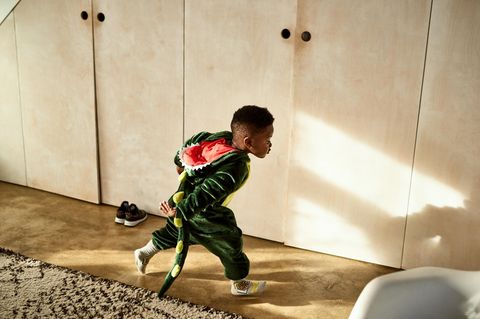 Ein Junge rennt im Dinokostüm durch das Zimmer