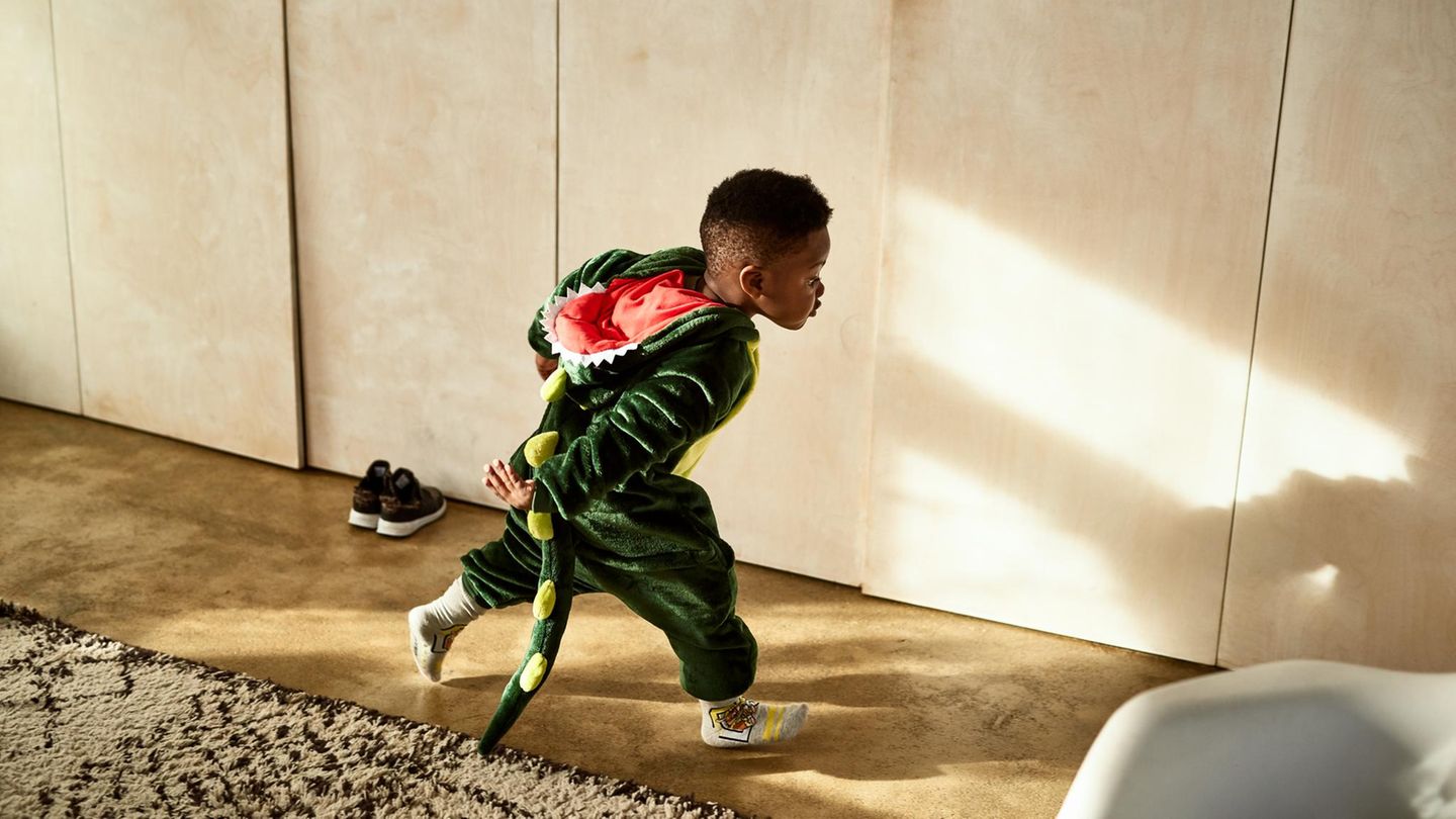 Ein Junge rennt im Dinokostüm durch das Zimmer
