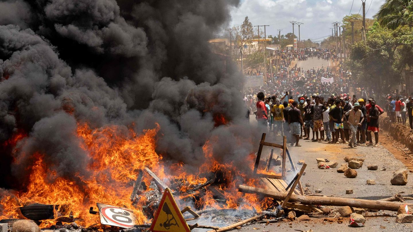 Antsiranana, Madagaskar. Regierungsgegner stehen während einer Demonstration gegen die Regierung neben einer brennenden Barrikade. Anhänger und Gegner der madagassischen Regierung wurden am Samstag zu Demonstrationen aufgerufen, während Sicherheitskräfte nach mehr als einer Woche tödlicher Unruhen Straßensperren errichteten