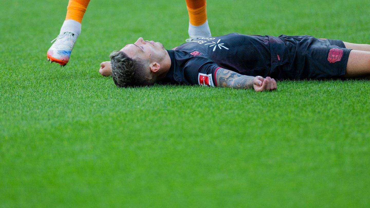 Bayer Leverkusens Kapitän Alejandro Grimaldo liegt nach einem Zusammenprall mit dem eigenen Mann benommen auf dem Boden. Foto: R