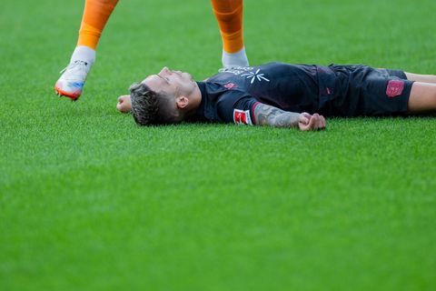 Bayer Leverkusens Kapitän Alejandro Grimaldo liegt nach einem Zusammenprall mit dem eigenen Mann benommen auf dem Boden. Foto: R